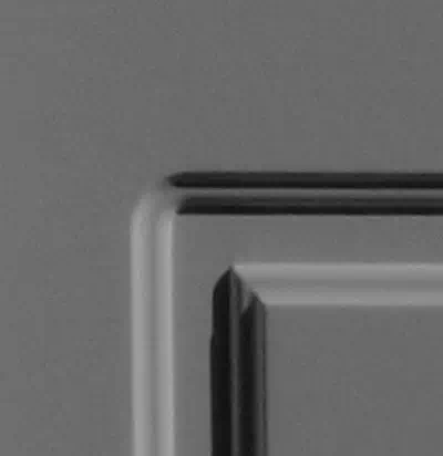 Widok na narożnik nowoczesnego przefrezowania stosowanego w kasetonach drewnianych drzwi zewnętrznych.